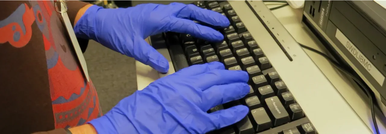 Hands in latex gloves typing on keyboard